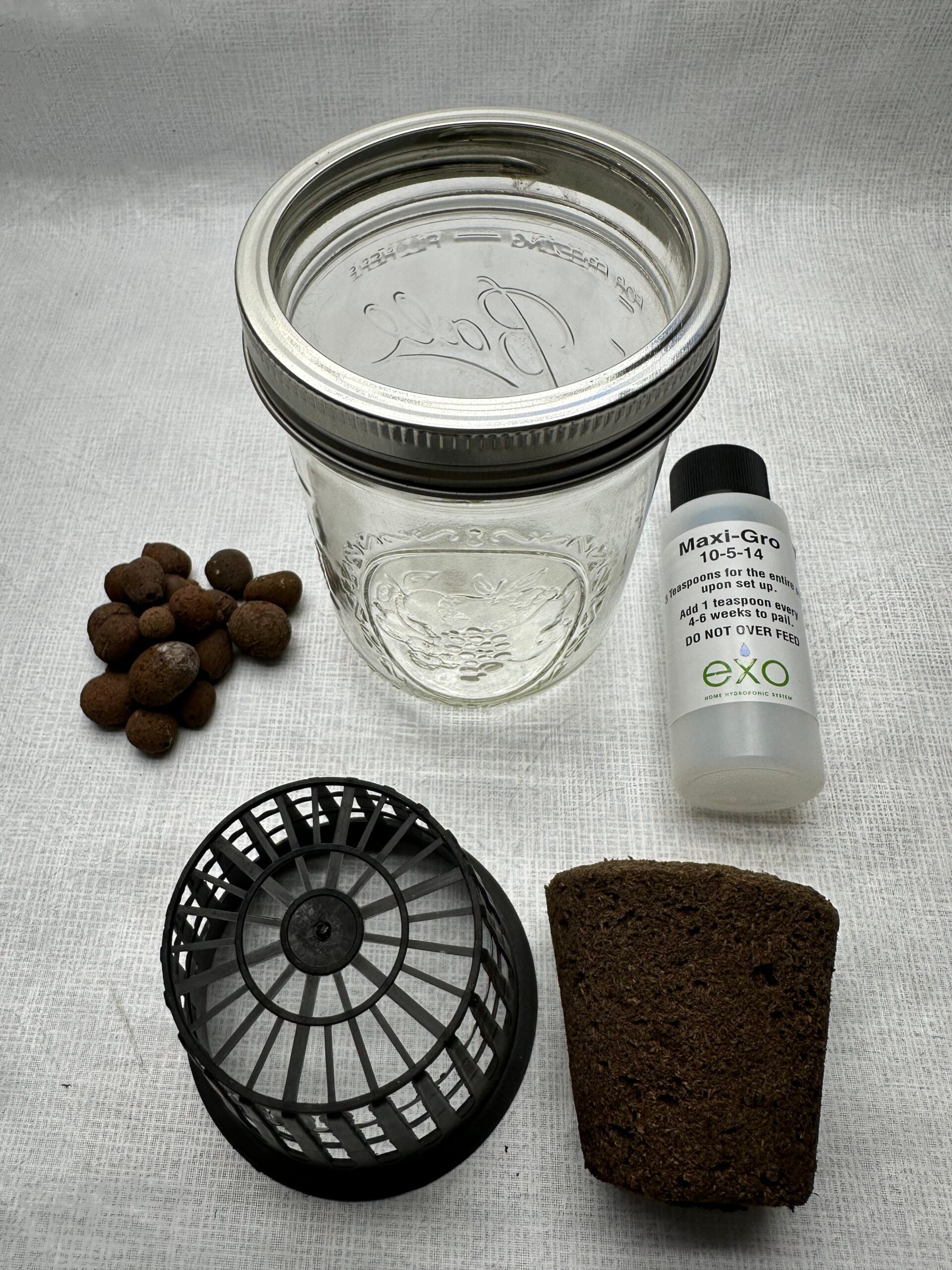 Exotowers 2 inch propagation kit components including glass jar, net pot, grow plug, clay pebbles and hydroponic nutrients